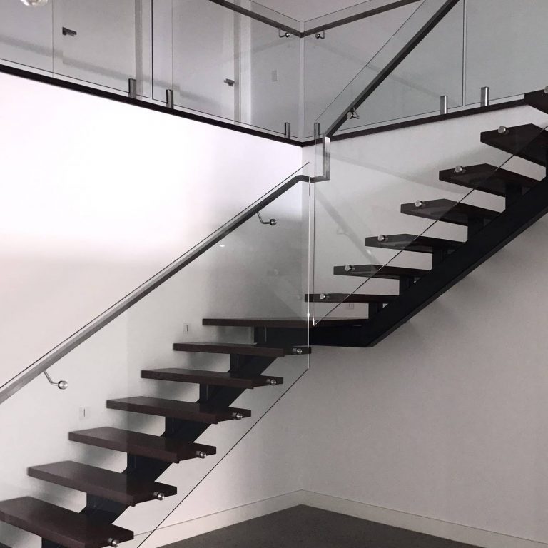 Steel spine monostring staircase with solid treads, glass baulstrade and modern handrail